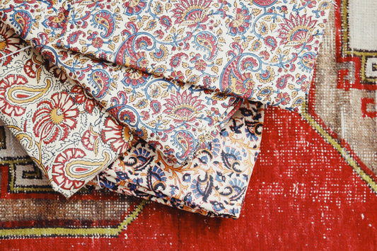 Four duvet different floral duvet covers stacked on top of rug.