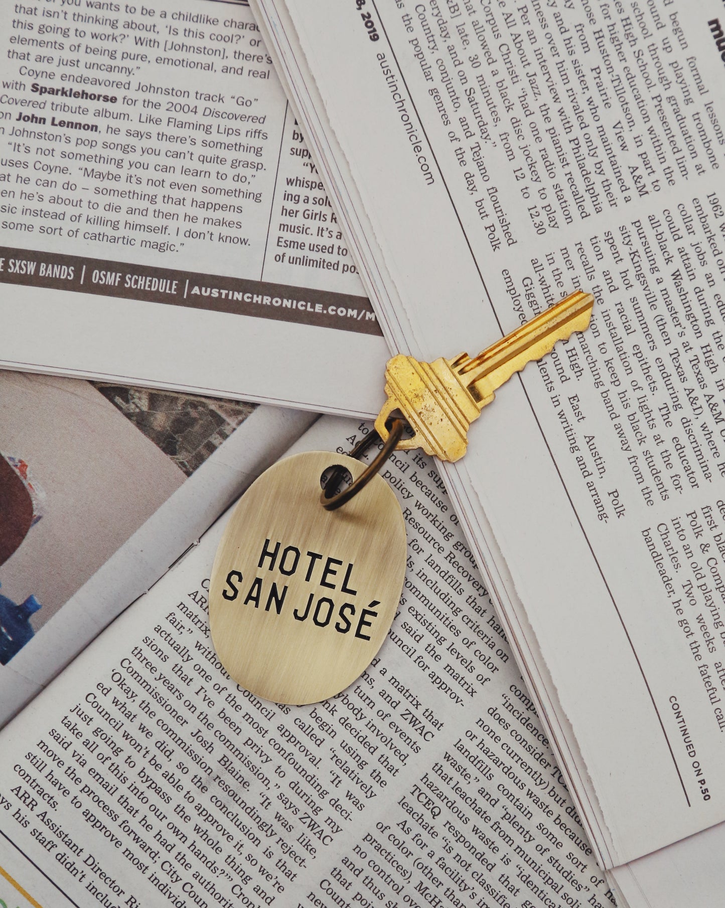 Gold key with 'Hotel San Jose' brass keychain on a newspaper background
