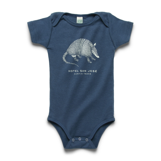 A blue short-sleeved baby onesie with a illustrated print of an armadillo and the text 'HOTEL SAN JOSE'.