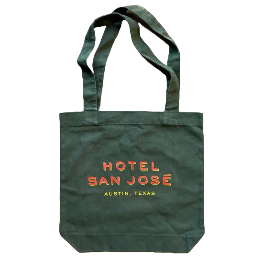 A green canvas tote bag with 'Hotel San Jose Austin, Texas' printed in orange and yellow lettering.