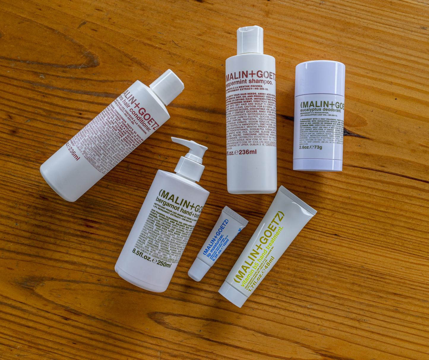 Photograph of malin and goetz apothecary products laying on top of wooden table.