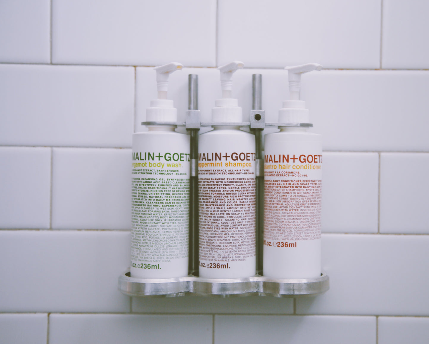 Photograph of mail and goetz products in pump bottles inside of hotel shower.