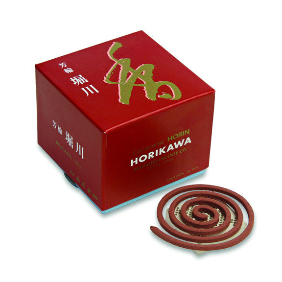 A red box with Japanese characters, containing incense coils and a holder, indicating it is Horikawa brand incense.