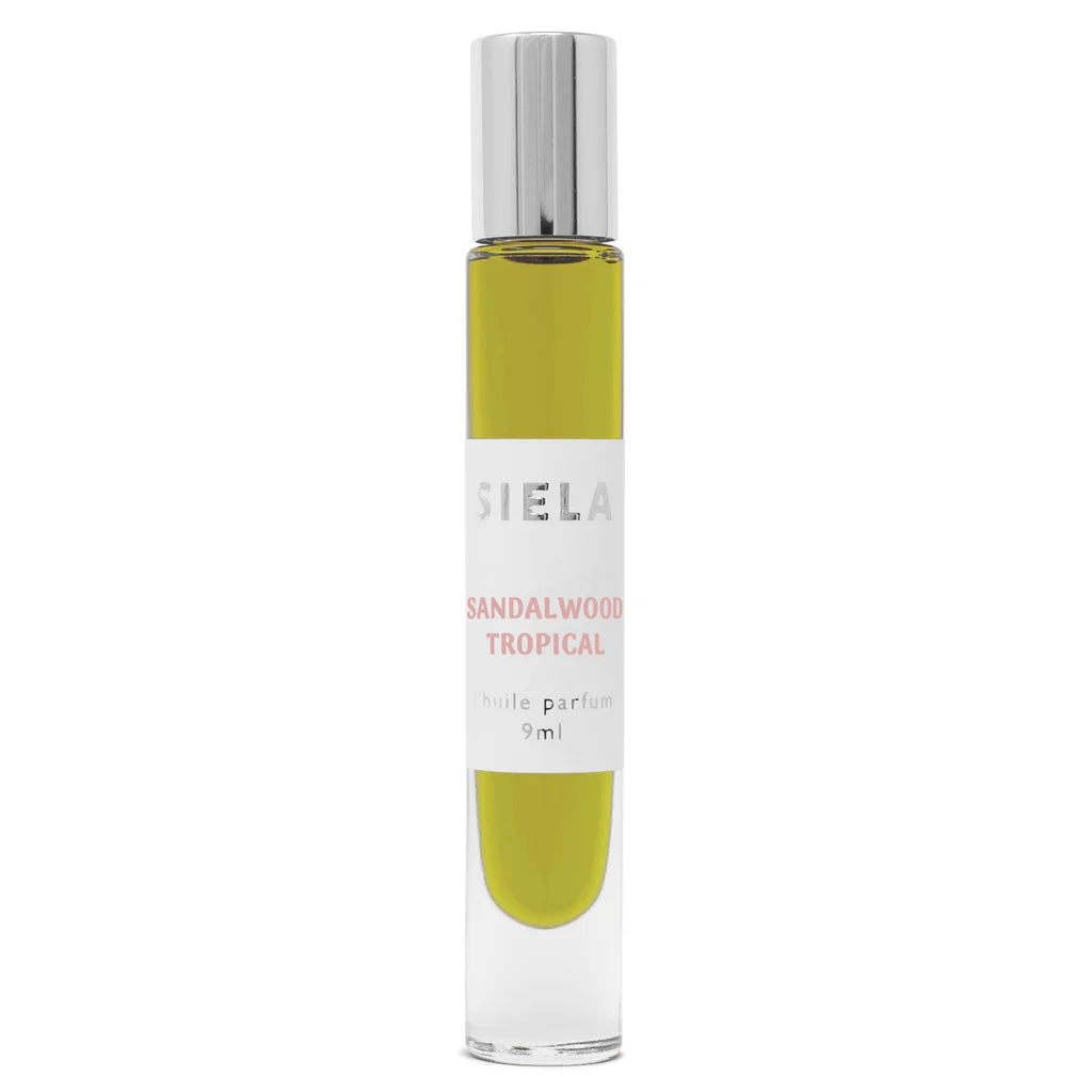 A roll-on bottle of Siela perfume with a label that reads 'Sandalwood Tropical'. The perfume bottle is clear with a green liquid inside, and it has a silver cap.