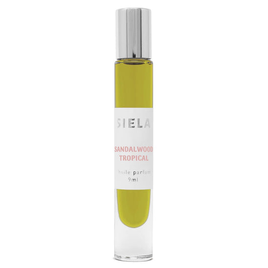 A roll-on bottle of Siela perfume with a label that reads 'Sandalwood Tropical'. The perfume bottle is clear with a green liquid inside, and it has a silver cap.