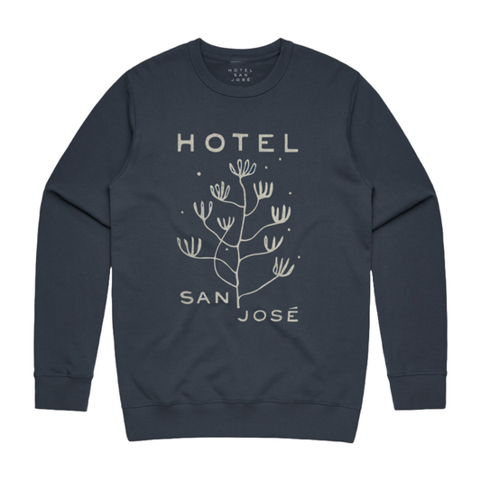 A navy blue crewneck sweatshirt with the text 'HOTEL SAN JOSÉ' and drawing of plant printed on the front.