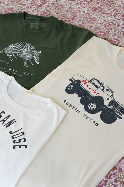 Three t-shirts with different designs on a patterned surface, all reading 'HOTEL SAN JOSE AUSTIN TEXAS'