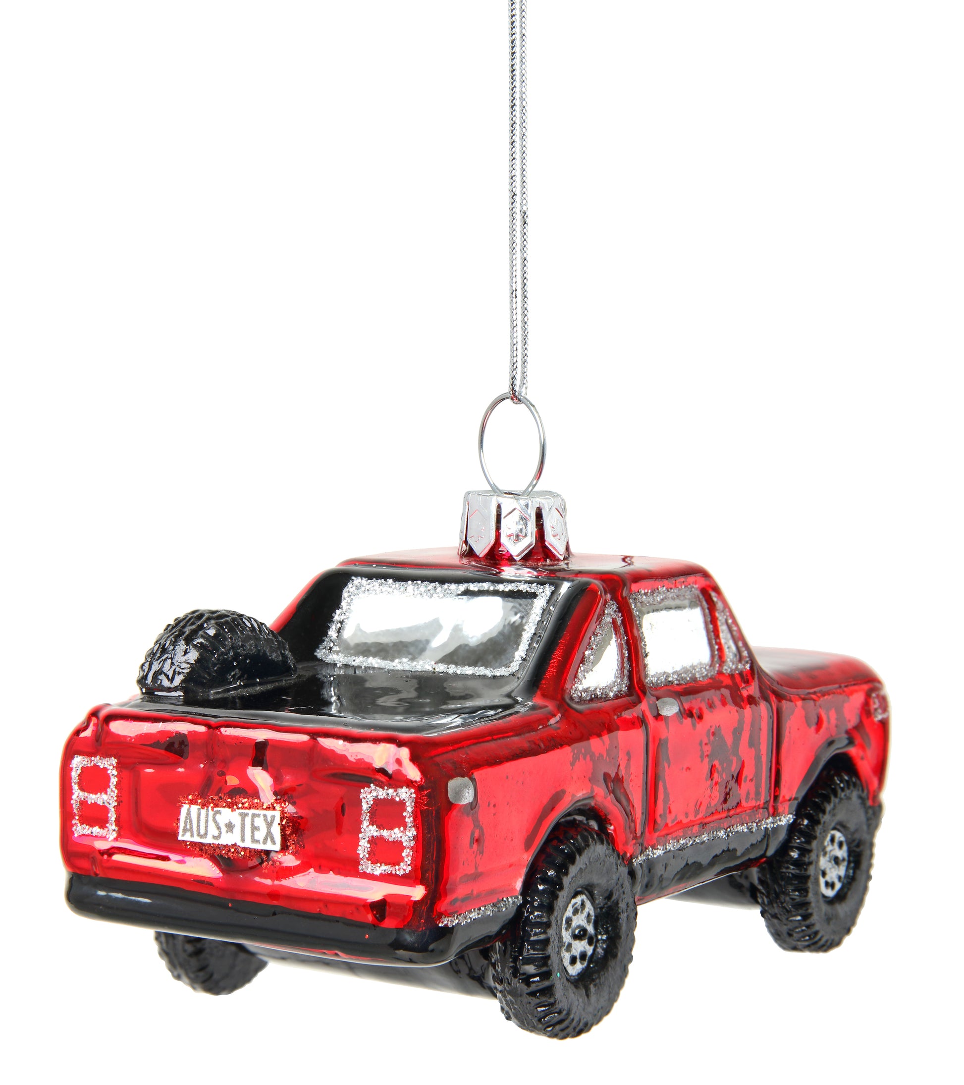 A red glass ornament in the shape of a vintage truck with 'AUS TEX' text on license plate. The ornament is adorned with glitter and has a loop for hanging.