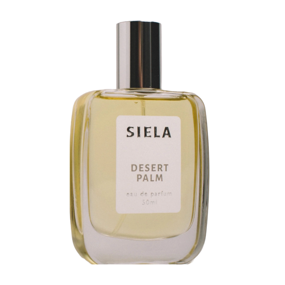 A bottle of Siela Desert Palm perfume with a white label and a clear yellowish liquid visible through the bottle.