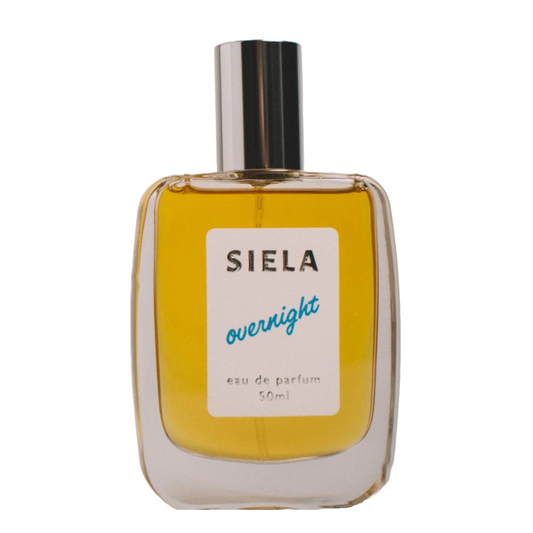 A bottle of Siela Overnight perfume with a clear label and a yellowish liquid visible through the transparent glass.