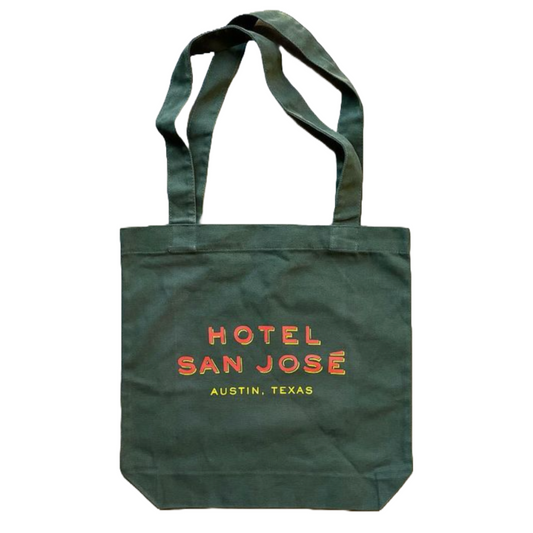 A green canvas tote bag with 'Hotel San Jose Austin, Texas' printed in orange and yellow lettering.