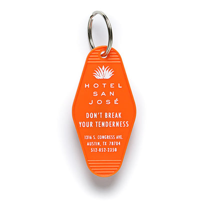 An orange vintage-style plastic keychain with white text and a motif that reads 'HOTEL SAN JOSE DON'T BREAK YOUR TENDERNESS?' and includes an illustration of an agave.