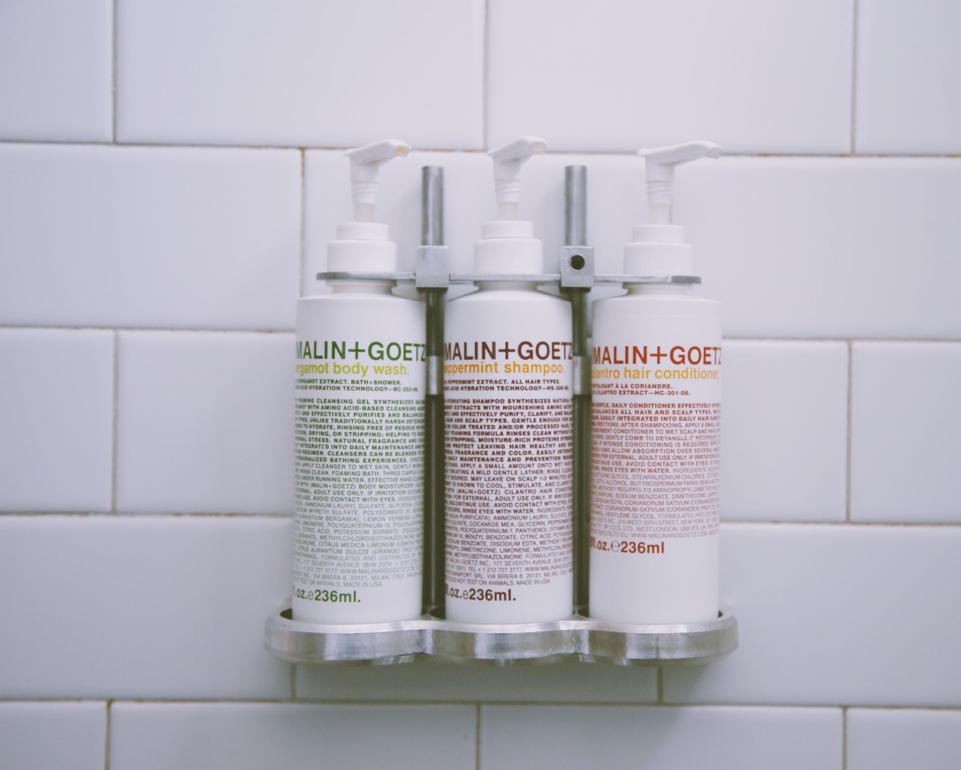 Photograph of mail and goetz products in pump bottles inside of hotel shower.