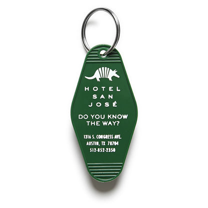 A green vintage-style plastic keychain with white text and a motif that reads 'HOTEL SAN JOSE DO YOU KNOW THE WAY?' and includes an illustration of an armadillo.