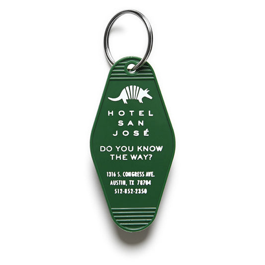 A green vintage-style plastic keychain with white text and a motif that reads 'HOTEL SAN JOSE DO YOU KNOW THE WAY?' and includes an illustration of an armadillo.