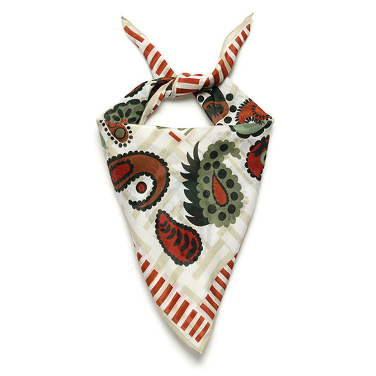 A bandana with a white and cream base featuring red and green paisley patterns folded and tied in a triangle.