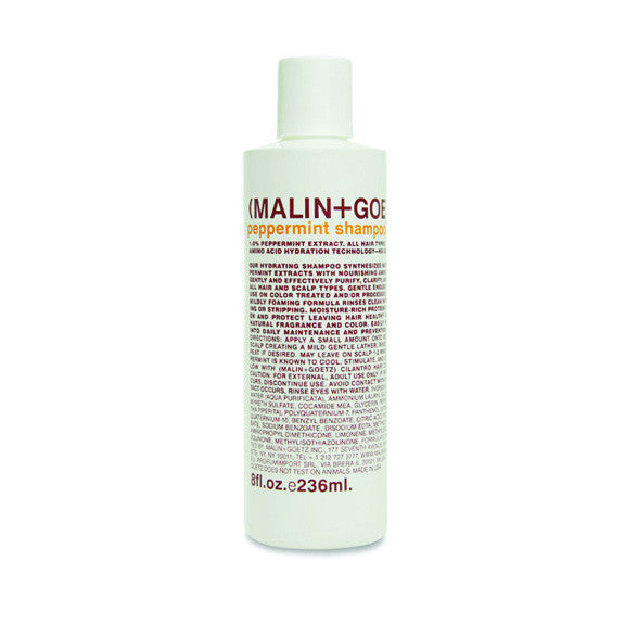A white bottle of MALIN+GOETZ peppermint shampoo with orange and brown label.