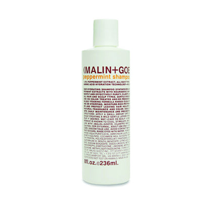 A white bottle of MALIN+GOETZ peppermint shampoo with orange and brown label.